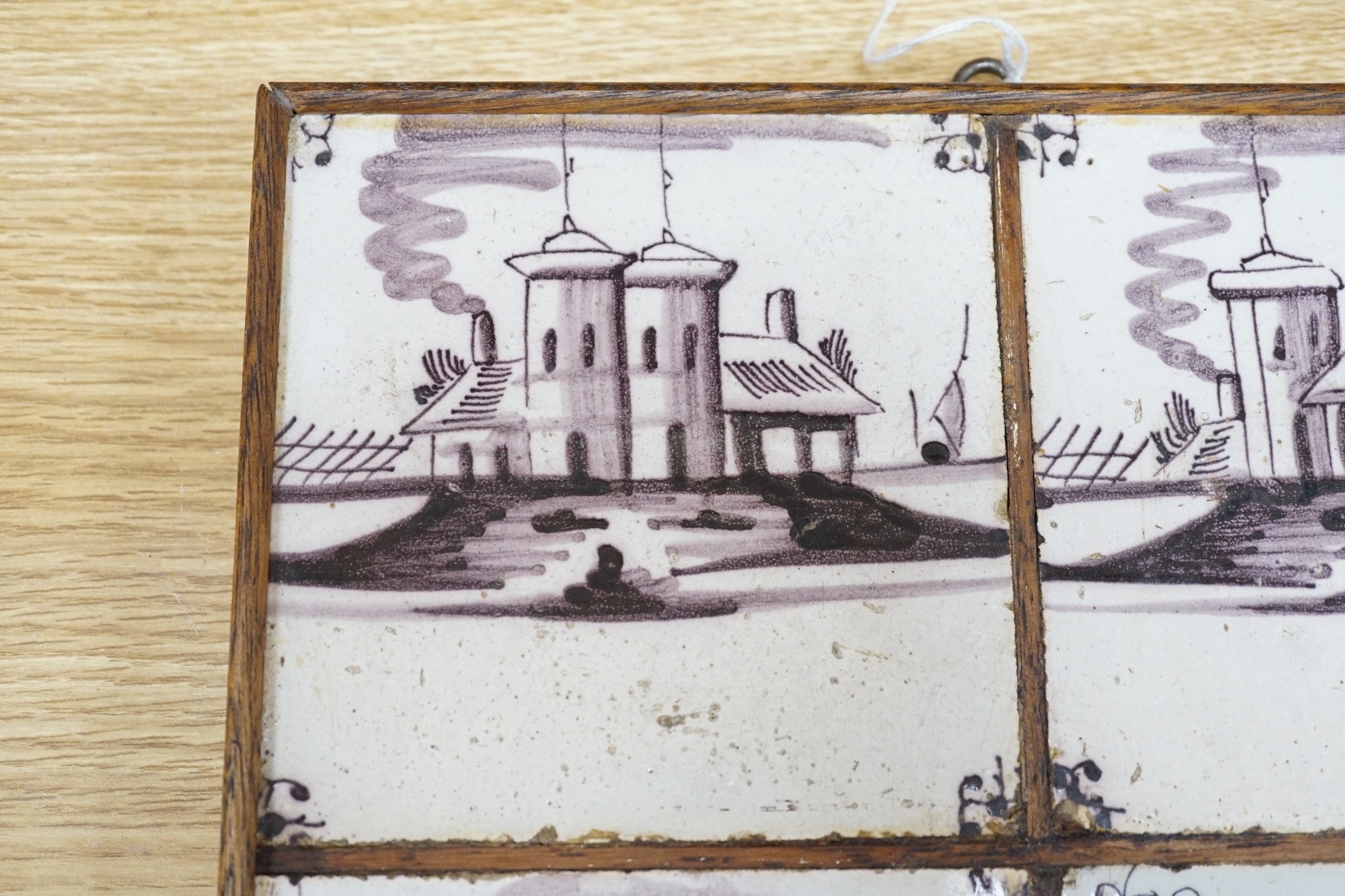 A set of four 18th century Dutch Delft manganese tiles decorated with buildings by a canal (frame 27cm)